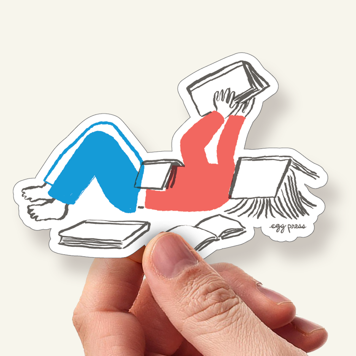 Sticker of a person lying down with books on a white background, Book Lover Reader Vinyl Sticker by Egg Press